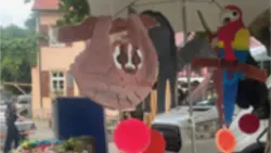 Ausgeschnittene, bemalte Pappen einiger Regenwaldtiere, aufgehängt an einem großen Sonnenschirm