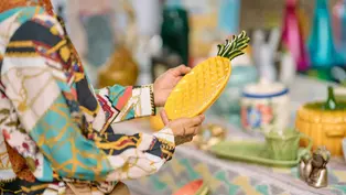 Ananasteller ©Natalia Blauth via Unsplash+ Eine Person hält einen Teller in Form einen Ananas in der Hand. Rundherum findet ein Flohmarkt statt.
