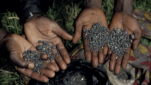 Vier Hände halten abgebautes Coltan. 