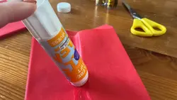 Ein Klebestift zieht einen Strich über eine Papiertüte. 