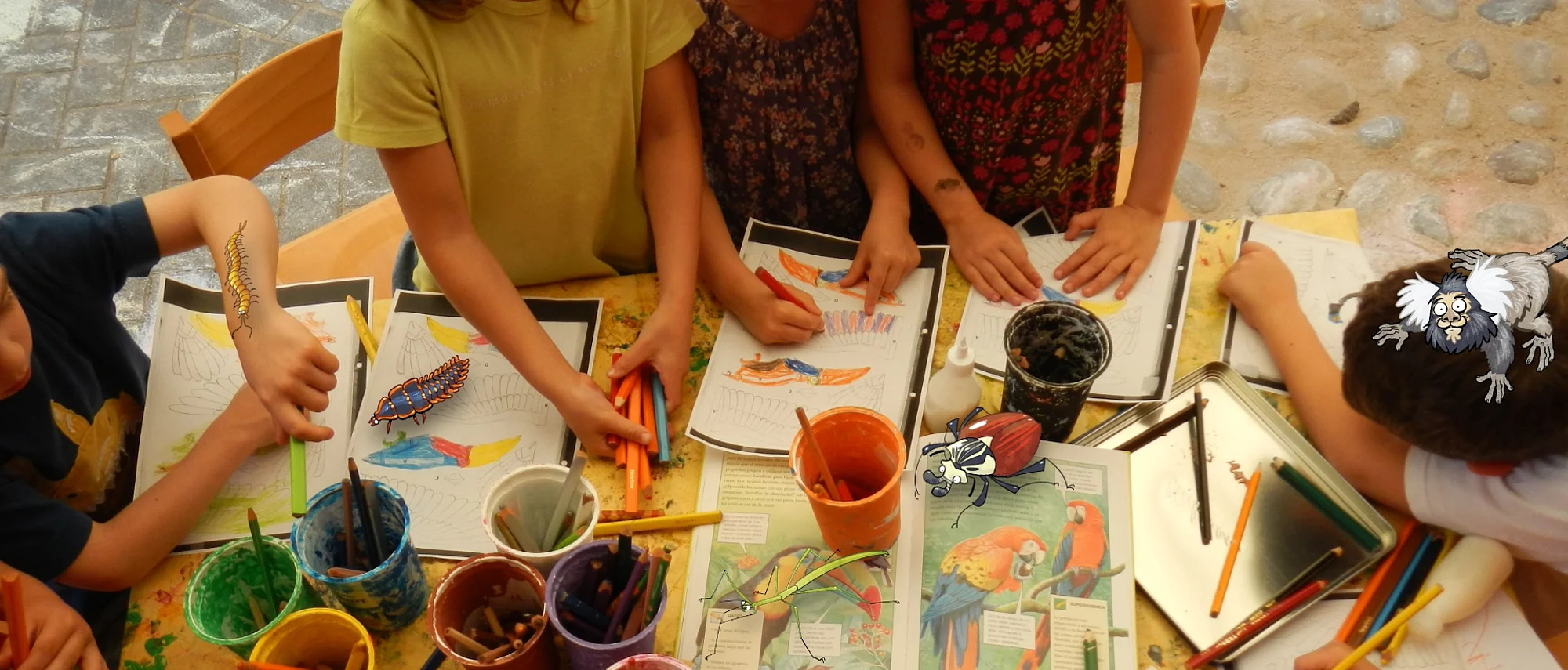 Kinder basteln an einem Tisch mit Papier - im Comic Stil hinzugefügt - mehrere Käfer und ein Äffchen.