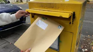 Ein großer, brauner Briefumschlag wird in einen gelben Briefkasten geworfen. 