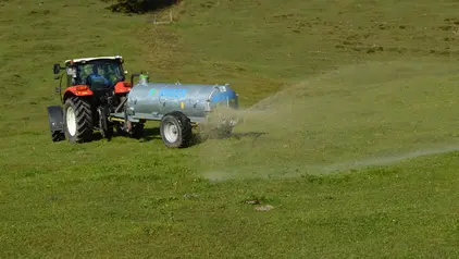 Ein Traktor der Gülle auf dem Feld verteilt.