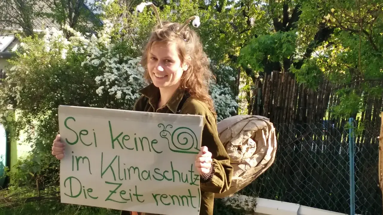 "Sei keine Schnecke im Klimaschutz - die Zeit rennt" ist der Slogan dieses Schildes, welches von einer verkleideten Person im Schneckenkostüm getragen wird.
