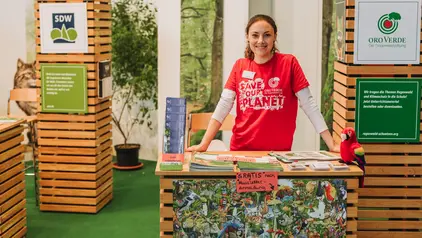 Infostand OroVerde ©OroVerde/H. Mennigen Das Bild zeigt eine Person hinter einem Infostand zum Thema Regenwald.