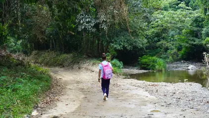 Melani´s Schulweg ©Centro Naturaleza/ S.Estevez Melani auf ihrem Schulweg entlang eines Waldes. Rechts ein Fluss und links Bäume.