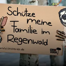 Kinder halten eine Schild mit der Aufschrift "Ich bin ein Klimaschützer" hoch - im Comic Stil hinzugefügt - ein Koboldmaki an der Schulter eines Kindes und ein großer Ameisenbär mit rausgestreckter Zunge. 