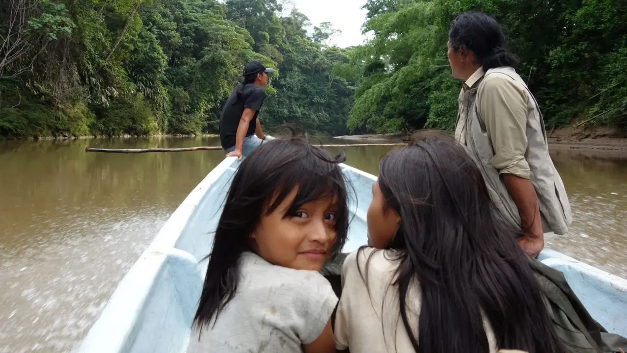 Kinder sitzen auf einem Boot, das über den Fluss durch den Regenwald fährt.