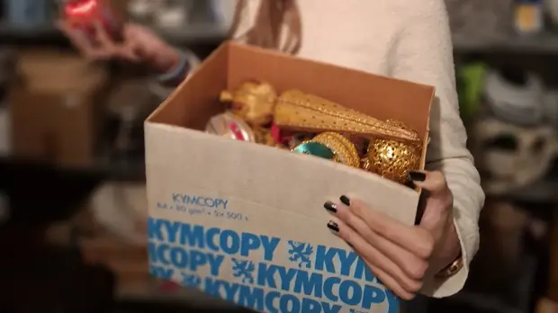 Ein Mädchen hält eine Kiste mit alter Weihnachtsdeko im Arm.