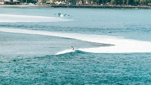 Ein Mensch surft im Meer vor der Insel La Réunion.