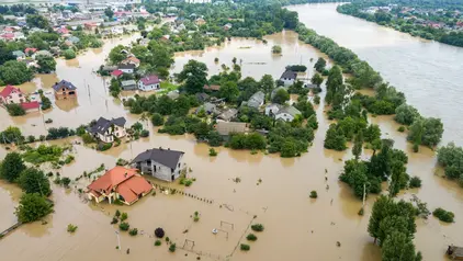 Eine überschwemmte Kleinstadt. Der vorbeilaufende Fluss führt Hochwasser.