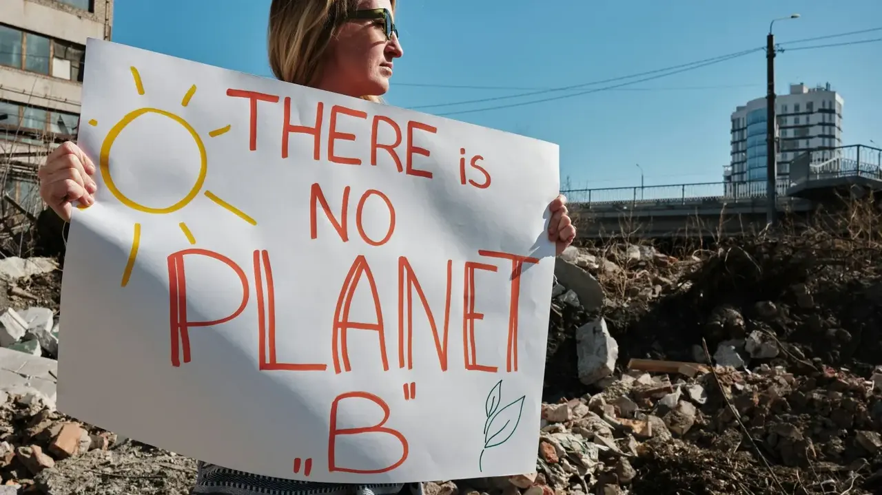 Ein Demoschild mit den Worten "There is no planet B" wird von einer Frau hochgehalten. 