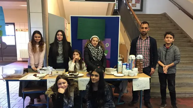 Kuchenverkauf der Nelson-Mandela-Schule ©Nelson-Mandela-Schule/ Bilal Akdag Das Bild zeigt eine Gruppe Schüler*innen und Ihre Lehrkraft am Kuchenverkaufsstand.