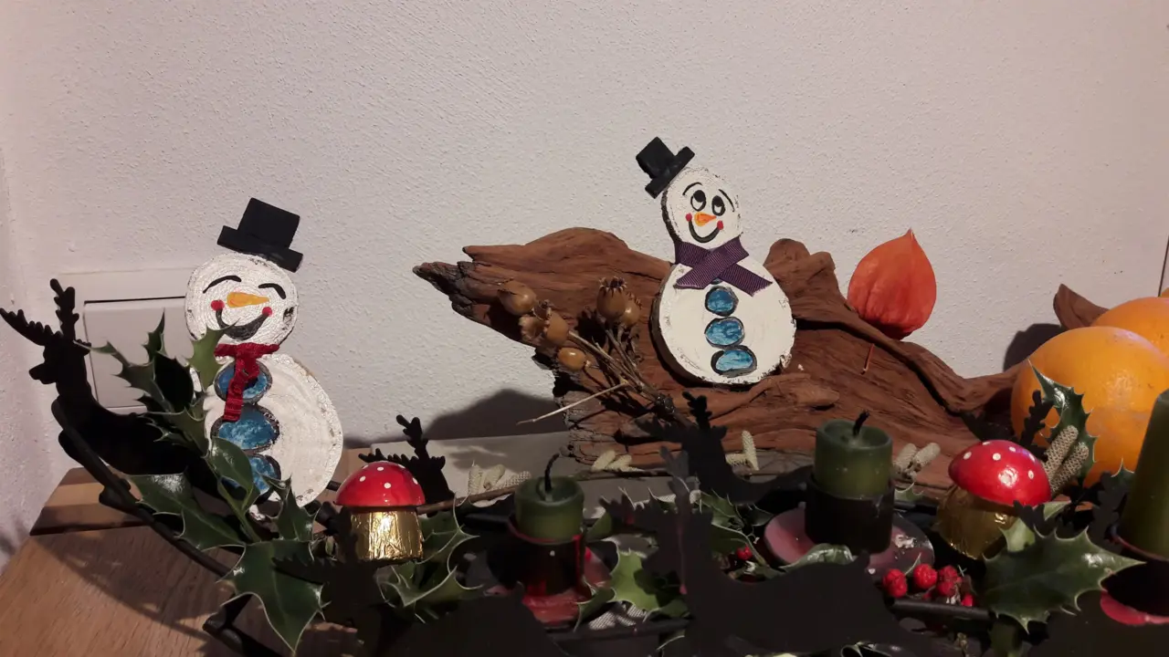 Schneemänner bemalt aus Pappe mit anderen Dekoelementen als Tischdekoration. 