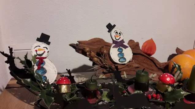 Schneemänner bemalt aus Pappe mit anderen Dekoelementen als Tischdekoration. 