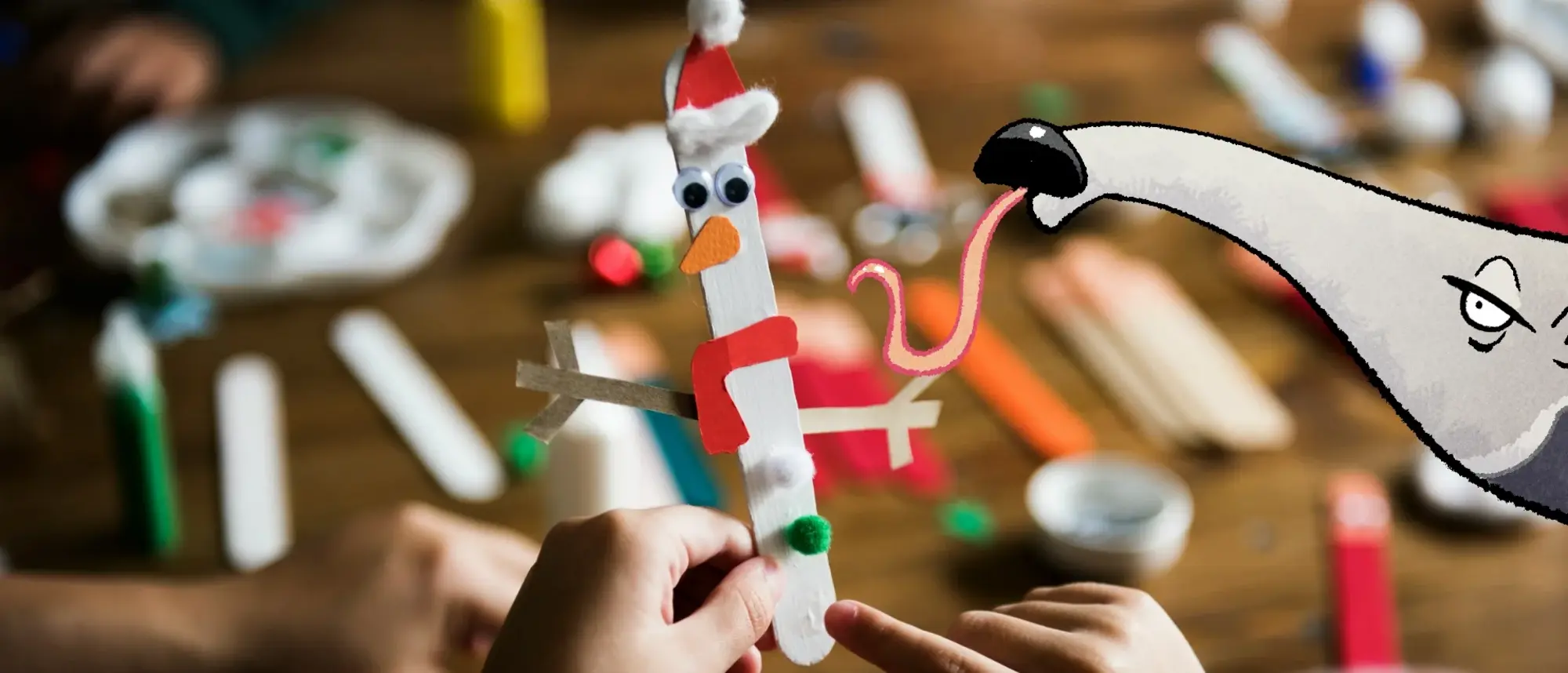 Ein gebastelter Schneemann aus einem Eisstiehl und Pappe - im Comic Stil hinzugefügt - ein Ameisenbär mit ausgestreckter Zunge.