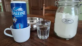 Zutaten für Salzteig auf einem Tisch: Milch, Glas Wasser, Salz und Mehl.
