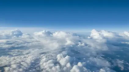 Wolken von oben betrachtet. Der Himmel darüber ist blau. 