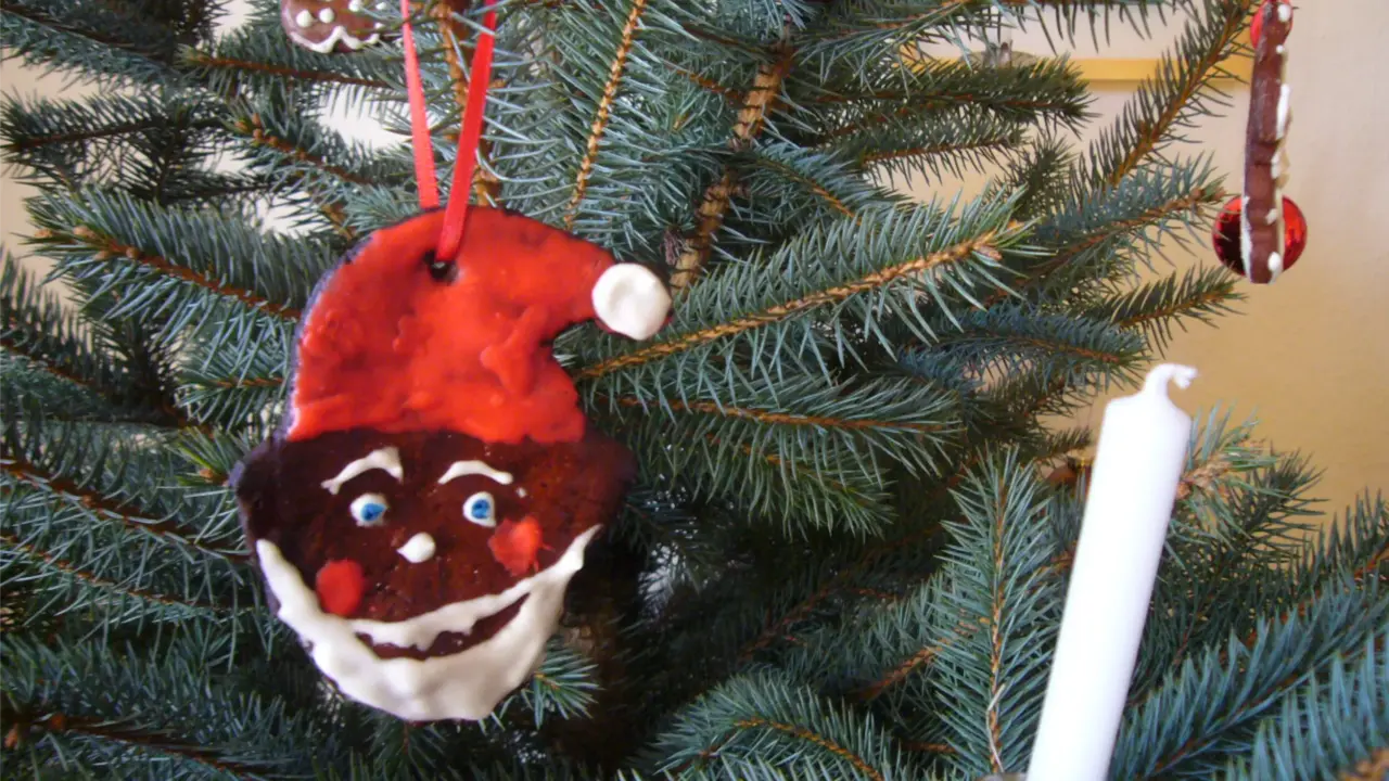 Gesicht des Weihnachztsmanns aus Lebkuchen gemacht als Anhänger am Weihnachtsbaum.