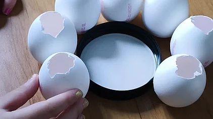 Eierschalen werden um einen Teller herum zusammengeklebt, sodass ein Kranz entsteht.