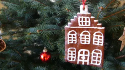 Lebkuchen mit Verzierung in Form eines Hauses als Anhänger am Weihnachtsbaum.