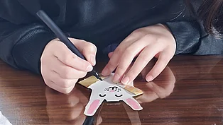 Ein Kind bemalt ein gebastelte Häschen aus Papier. 