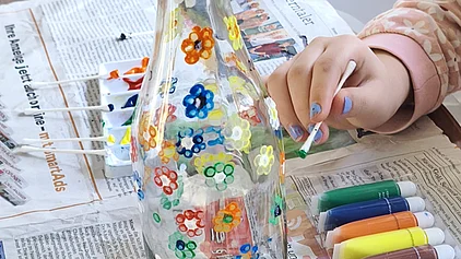 Ein Kind tupft mit einem Wattstäbchen kleine Blumen auf eine Glasvase!