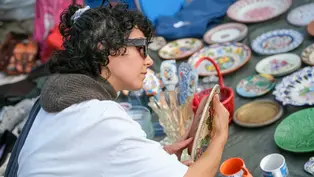 verschiedee Porzellanteller ©Hrant Khachatryan via Unsplash+ Verschiedene Teller stehen auf einem Flohmarkt Tisch. Eine Frau guckt sich einen Teller an.