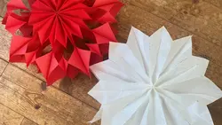 Zwei Sterne aus Papier gebastelt auf einem hölzernen Untergrund.