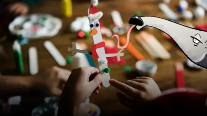 Ein gebastelter Schneemann aus einem Eisstiehl und Papier - im Comic Stil hinzugefügt - ein Ameisenbär mit ausgestreckter Zunge.