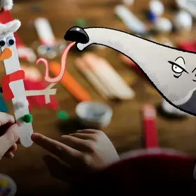 Ein gebastelter Schneemann aus einem Eisstiehl und Papier - im Comic Stil hinzugefügt - ein Ameisenbär mit ausgestreckter Zunge.