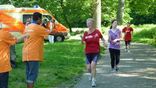 Eine Laufstrecke in einem Park ©OroVerde Läuferin auf der Strecke. Hilfskräfte halten ihr ein Band entgegen.